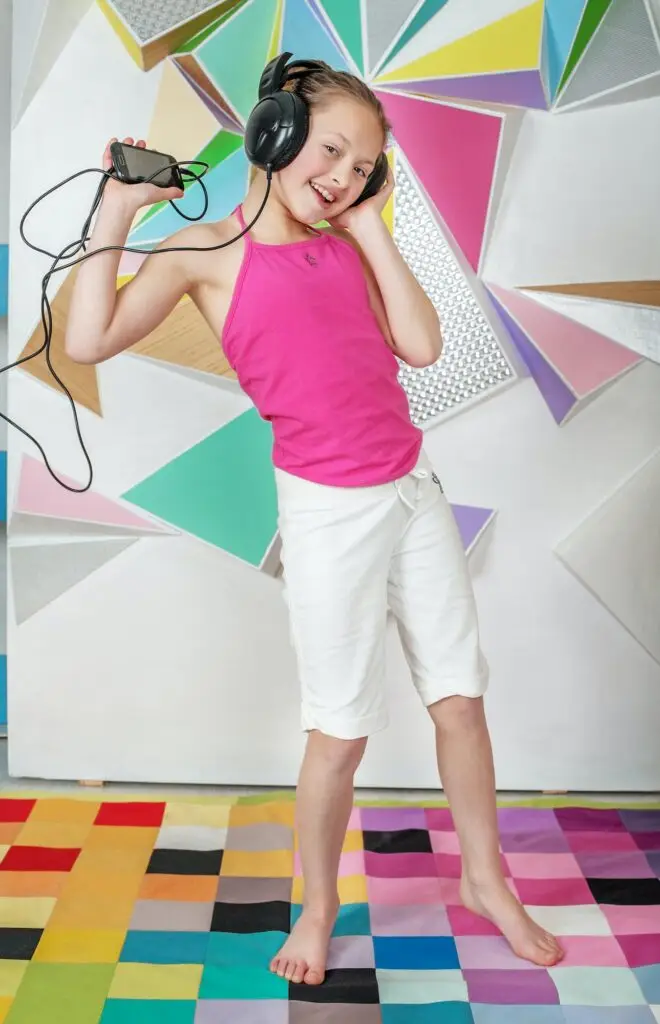 Child girl listens to music and dances. The concept of music and childhood.
