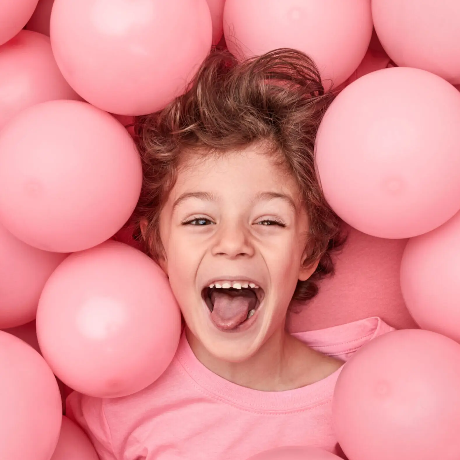 Excited kid playing in balloons